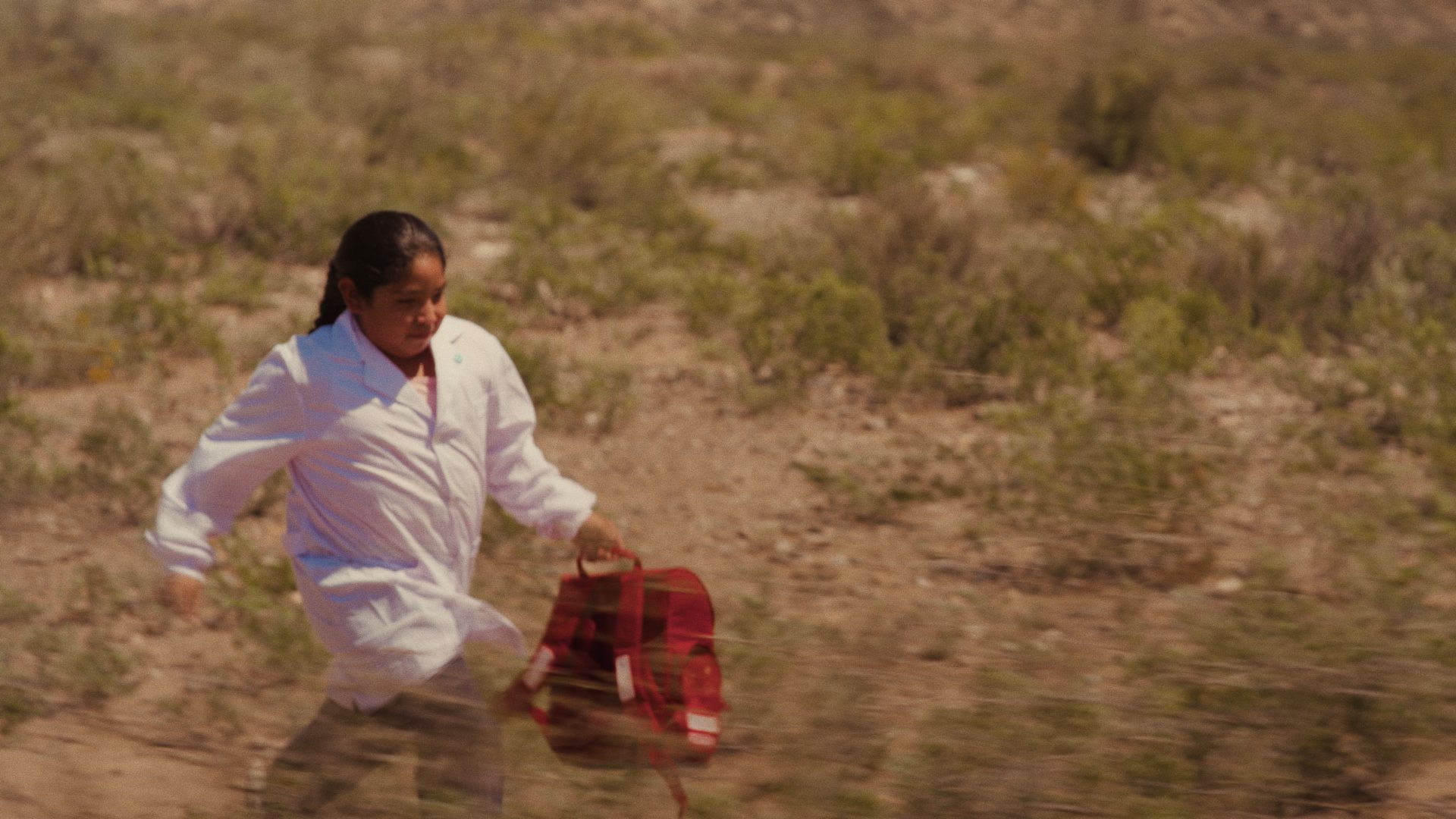 Ramona running through the desert with her red backpack